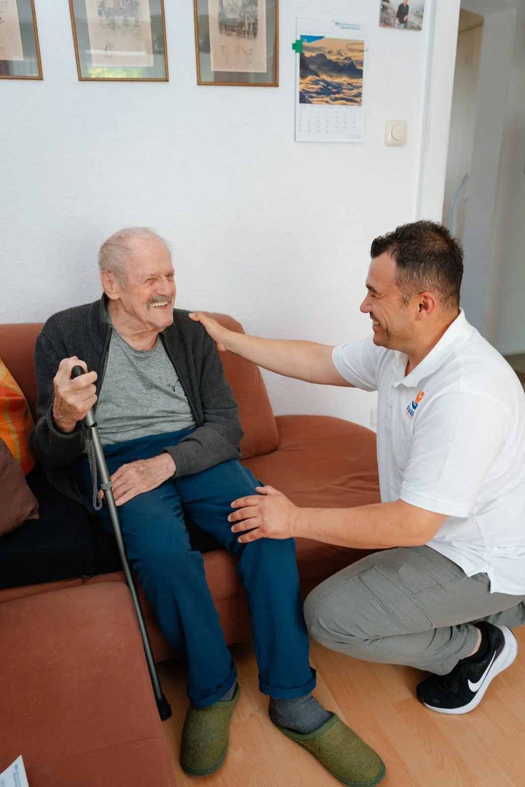 Pflegekraft von Bavaria Vitalpflegedienst bespricht mit einem Senior im Sessel den Pflegeantrag