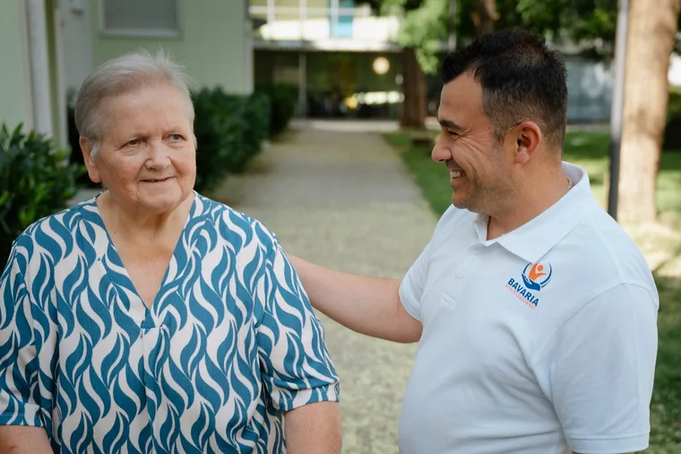 Pflegekraft von Bavaria Vitalpflegedienst im Gespräch mit einer Seniorin beim Spaziergang