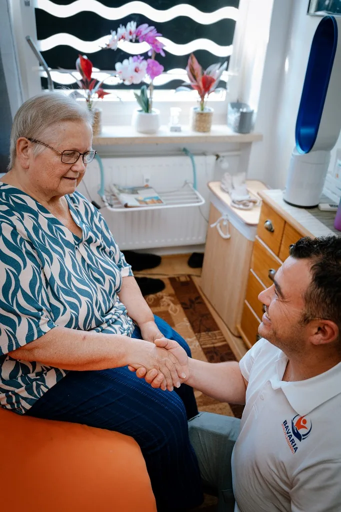 Pflegekraft von Bavaria Vitalpflegedienst hält einfühlsam die Hand einer Seniorin bei der Grundpflege zu Hause in München