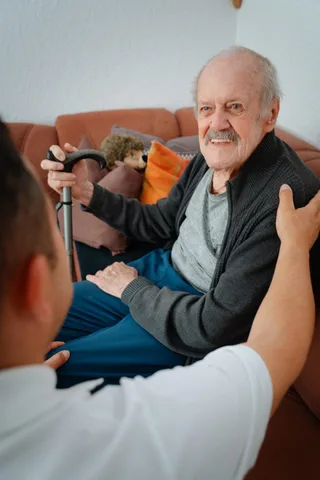 Senior mit Gehstock im Gespräch mit einer Pflegekraft von Bavaria Vitalpflegedienst — wir versorgen Schwabing-Freimann in München